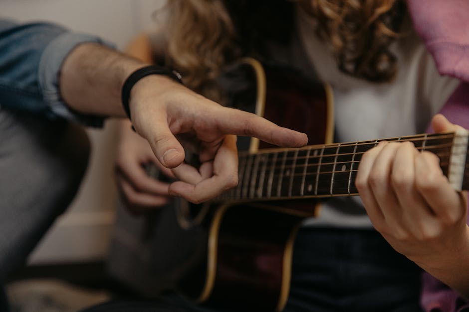 A detailed view of hands during a guitar lesson, focusing on finger placement and technique.
